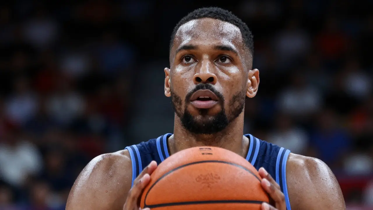 Soustředěný basketbalista při střelbě z volného hodu v zaplněné aréně.