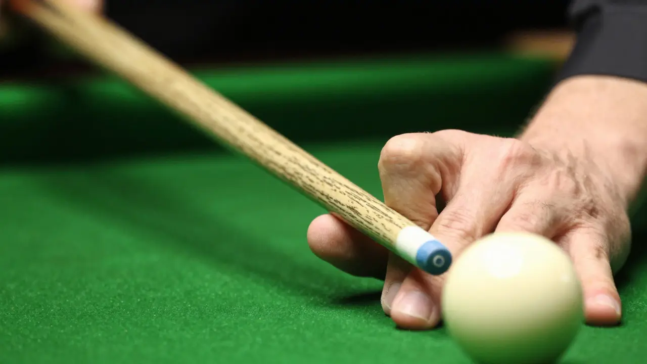 Close-up of hands holding a chalked snooker cue stick